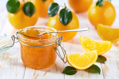 Beyaz bir masada taze portakal dilimleri ile portakal reçeli. Konserve kavramı.