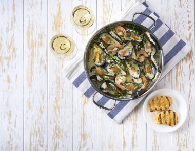 Beyaz ahşap bir masada midyeli krema çorbası ve beyaz şarap..