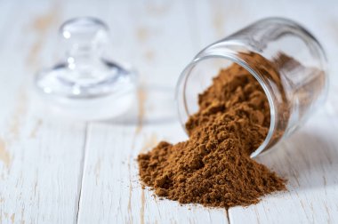 Cam bir kavanozdan beyaz bir tahta masaya tarçın tozu döküldü..