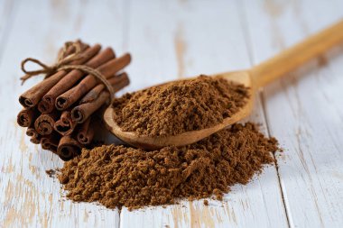 Tahta bir kaşıktan beyaz bir tahta masaya tarçın tozu döküldü. Seçici bir odak noktası..