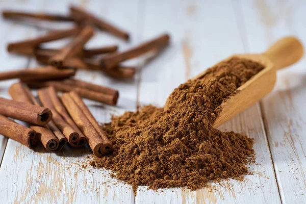 Tahta bir kaşıktan beyaz bir tahta masaya tarçın tozu döküldü..