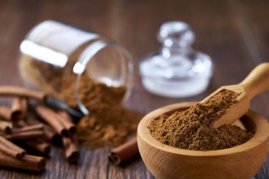 Yakın plan tarçın tozu. Tahta bir kasede. Koyu ahşap bir masada..