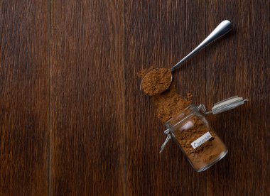 Cam bir kavanozdan beyaz ahşap bir masaya tarçın tozu döküldü..