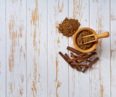 Tahta bir kasede tarçın tozu, açık tahta bir masa, üst manzara..