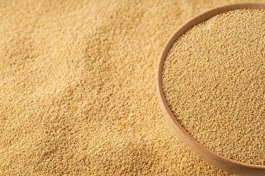 Tahta kabın içindeki taneler seçici bir odak noktası olan hafif bir masaya saçılmış..