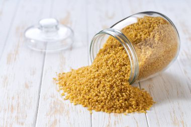 Cam bir saklama kavanozundan çıkan organik kuru bulgur, seçici bir odak noktası..