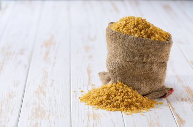 Çuvalda kuru bulgur, organik kuru bulgur. Çuval bezinde organik kuru bulgur ve bulgur yığını..