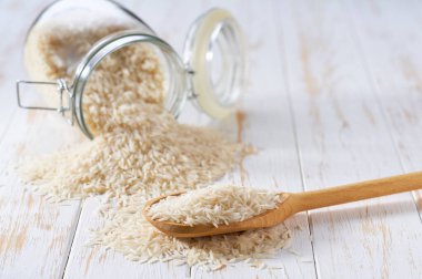 Tahta kepçe içinde organik beyaz basmati pilavı ve cam saklama kavanozunda seçici bir odak noktası var..