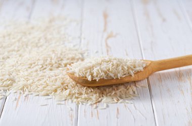 Beyaz basmati pilavı, tahta kaşıktan seçici bir odak noktası olan, hafif bir masanın üzerine dökülür..