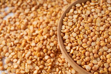 Kuru, sarı bezelyeler ahşap kaseden seçici bir odak noktası olan bir masaya saçıldı..