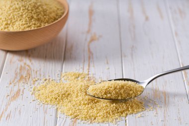 Aydınlık bir masada saf kuskus ile metal kaşık, seçici odak.