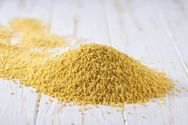 Işık masasında darı sarısı tanecikler, seçici bir odak noktası. Aydınlık bir masaya darı yığını, seçici odak.