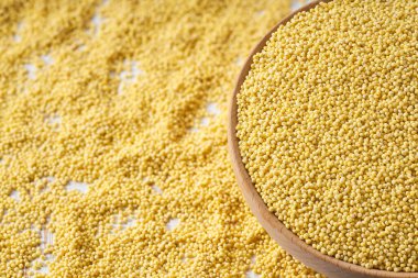 Organik darı sarı taneleri ahşap kaseden seçici bir şekilde seçilmiş bir masanın üzerine serpiştirilir..