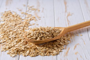 Yuvarlanmış kuru yulaf ezmesi, tahta kaşıktan seçici bir odak ile hafif bir masaya dökülür..