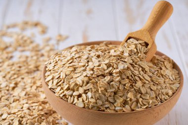 Kurutulmuş organik yulaflar ahşap kaseden seçici bir odak noktası olan ışıklı masaya saçılmıştır..