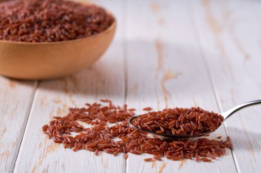 Aydınlık bir masada çiğ kırmızı pirinç ile metal kaşık, seçici odak.