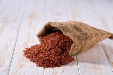 Torbada organik kırmızı pirinç. Organik kırmızı pirinç torbası. Çuval bezinde organik kırmızı pirinç ve pirinç yığını..