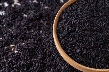 Çiğ organik pirinç taneleri ahşap kaseden seçici bir odak noktası olan bir masaya saçıldı..