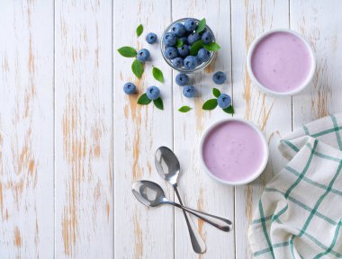 Beyaz bir masada seramik bir kasede taze yaban mersinli ev yapımı meyve püresi..