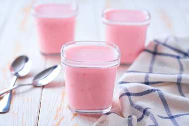 Beyaz bir masada kavanozda ev yapımı pembe yoğurt, seçici bir odak noktası..