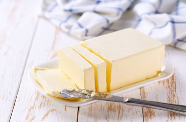 Mutfak masasında beyaz bir tabakta bir kalıp tereyağı, seçici bir odak..