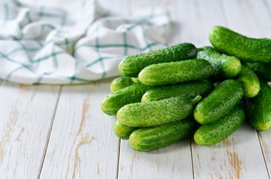 Beyaz ahşap bir masada, metin için kopyalama alanı olan organik salatalıklar..