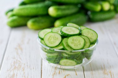 Salatalıklar, tahta bir masada, cam bir kasede, seçici bir odak noktası olan organik salatalıklar..