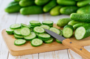 Tahta bir masanın üzerindeki kesme tahtasındaki organik salatalıklar, seçici bir odak noktası..