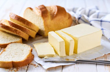 Mutfak masasında tereyağlı buğday ekmeği dilimleyin. Beyaz ahşap bir masada taze tereyağlı lezzetli buğday ekmeği..
