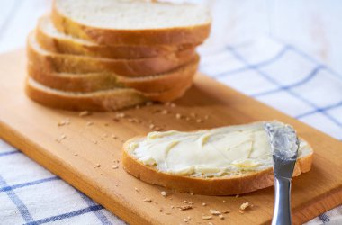 Açık ahşap bir masada buğday ekmeği dilimleri, seçici bir odak noktası..