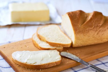 bir dilim buğday ekmeğine tereyağı sür kesme tahtasına, seçici odaklanma.