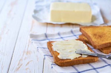 Tereyağını kesme tahtasına altın çıtır bir tost parçasına sür, seçici bir odak noktası..
