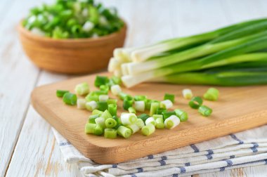 Tahta kesme tahtasının üzerinde doğranmış taze taze soğan yığını, seçici odaklanma.