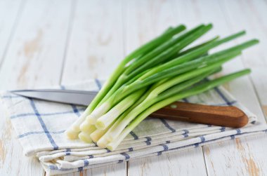 Genç yeşil soğanlar ya da soğanlar beyaz bir masada, seçici bir odak noktası.