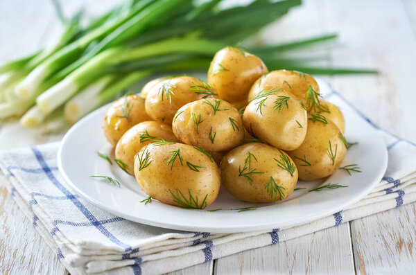 boiled young potatoes with butter and fresh dill in a kitchen table.