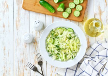 Lahana salatası. Beyaz ahşap bir masada ev yapımı lahana, salatalık ve dereotu salatası..