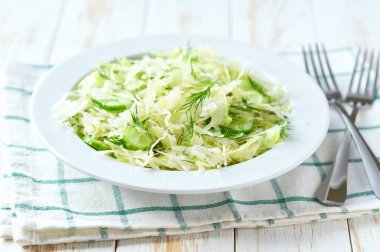 Beyaz ahşap bir masada taze lahana ve salatalık dereotlu salata, seçici bir odak..