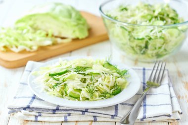 Beyaz ahşap bir masada taze lahana ve salatalık dereotlu salata, seçici bir odak..