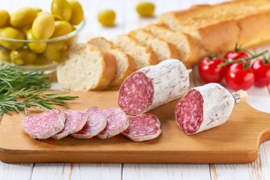 Tahtada dilimlenmiş İspanyol sosisi, zeytin ve ekmeğin yanında..
