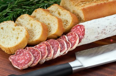 Domuz eti dilimleri kurutulmuş salam sosisi ve ekmek dilimleri ahşap bir masada..