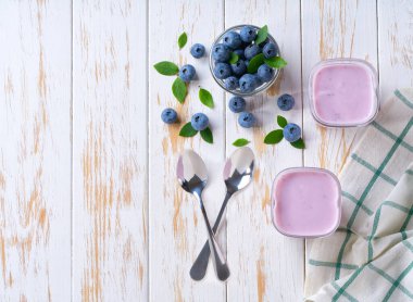 İki porsiyon ev yapımı meyve püresi. Arka planda cam kavanozlarda taze yaban mersini var..