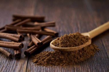 Tahta bir kaşıktan siyah bir tahta masaya tarçın tozu döküldü..