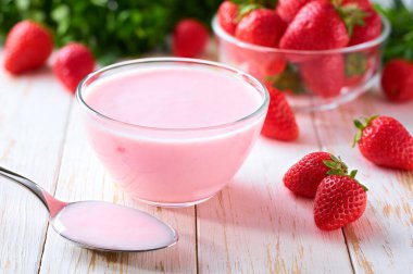 Pembe yoğurt, cam bir kasede, beyaz bir masada kaşık, seçici bir odak noktası..