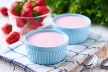 Beyaz bir masada taze çilekle seramik bir kasede ev yapımı çilekli smoothie, seçici bir odak..