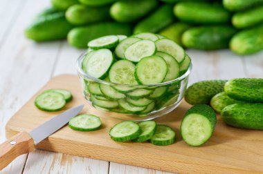 Aydınlık bir masada cam bir kasede doğranmış taze salatalık dilimleri. Taze salatalık..