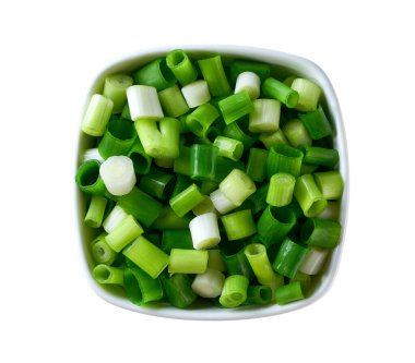 Beyaz arka planda izole edilmiş seramik bir kasede doğranmış taze soğan. Kesme yolu. Üst görünüm.