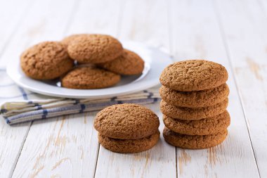 Yuvarlak yulaf ezmeli kurabiyeler beyaz bir masada seramik kasede, seçici bir odak noktası..