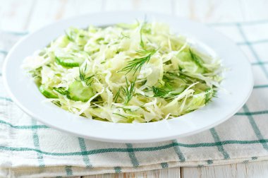 Tahta bir masada taze sebze salatası, salatalık ve dereotu..