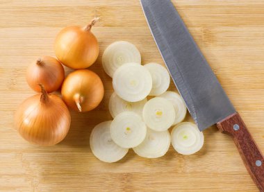 Tahta bir kesme tahtasının üstünde doğranmış Syellow soğanı. Tam sarı soğan ve kesme tahtasının üstünde bir bıçak..