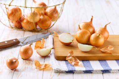 Tahta bir masada sarı soğanlar, seçici bir odak noktası. Metin için alanı kopyala.